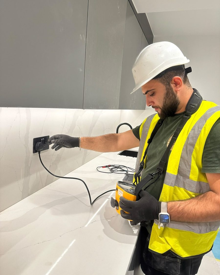 Electrician carrying out electrical testing in a modern London kitchen